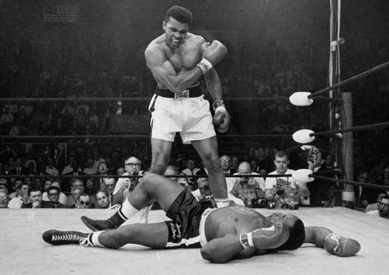 El campeón de peso pesado Muhammad Ali se encuentra sobre el retador caído Sonny Liston poco después de derribarlo con un fuerte golpe de derecha en la mandíbula en Lewiston, Maine en 1965. Las reglas de Queensberry fueron las primeras en exigir el uso de guantes en el boxeo y el boxeo moderno se basa en este código